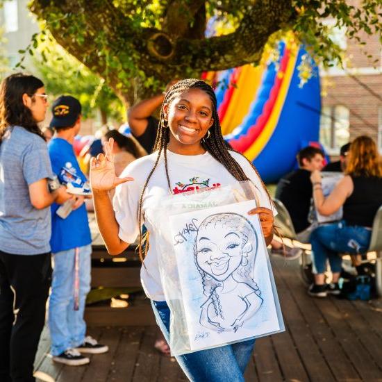 Female student holding a caricature drawing of herself.